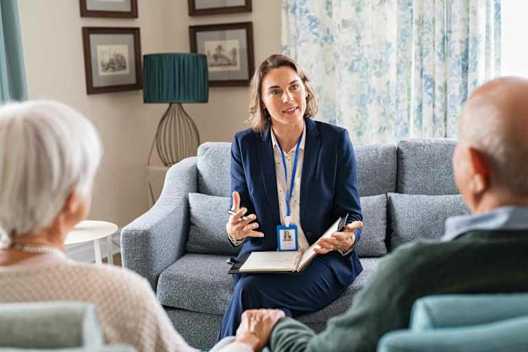 Social worker speaking to elderly couple in their home