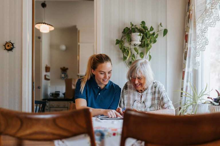 Social worker helping elderly client at table