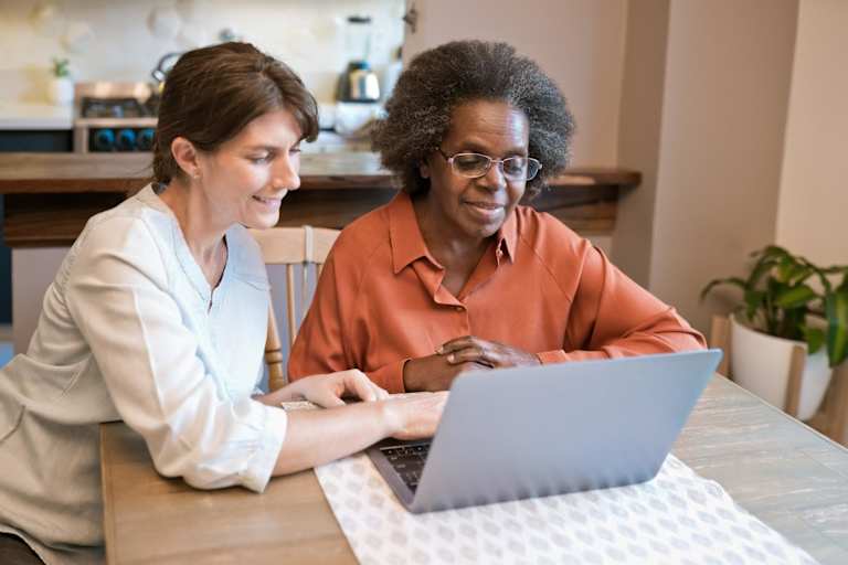 Social worker helping elderly client on computer