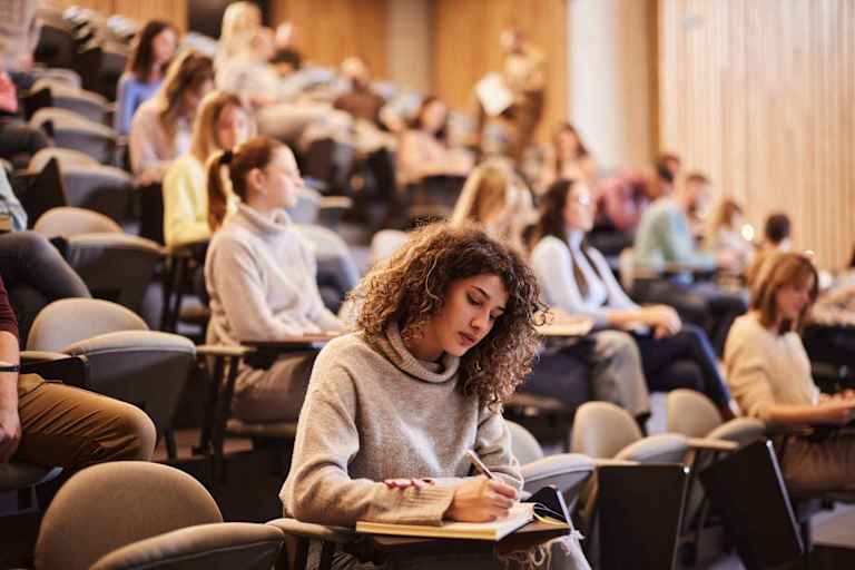 College student taking notes in lecture hall