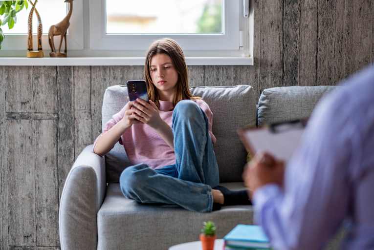 Teenage girl on smartphone in therapist's office