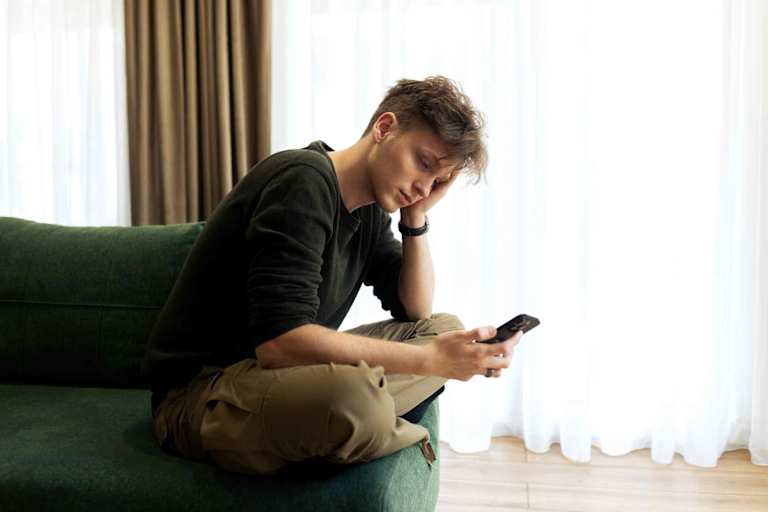 Sad young man typing on smartphone